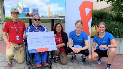 Gruppenbild: Fünf Menschen hocken in einer Reihe. Eine Person hält einen großen Scheck, auf dem die Spende von 2.500 € geschrieben ist.