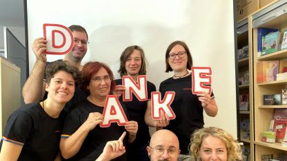 Gruppenbild: Mitarbeitende der AIDS-Hilfe. Jede Person trägt einen Buchstaben, die zusammen das Wort "Danke" ergeben.