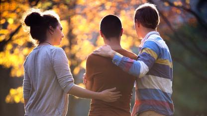 3 Freunde stehen nebeneinander, sich gegenseitig in den Armen haltend. 