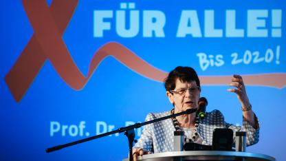 Rita S&uuml;ssmuth am Redepult, Hintergrund: eine rote Aidsschleife und die Schrift 