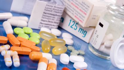 Medikamentenpackungen, Tabletten und Kapseln in verschiedenen Farben auf einer blauen Fläche