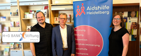 Peter Abelmann, Michael Hoffmann und Juliane Schurig stehen neben einem Roll-up der Aidshilfe