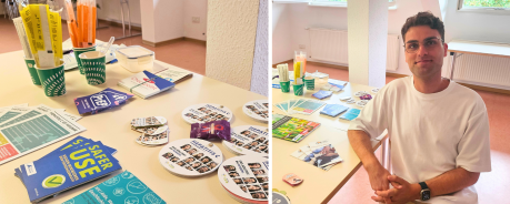 Julius sitzt vor einem Tisch mit vielen Infomaterialien und Sachen, die er f&uuml;r HIV und STI-Tests braucht