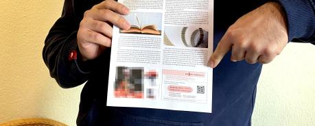 Eine Person hält die Uni-Zeitschrift "Campus HD" in die Kamera und zeigt auf eine Anzeige der AIDS-Hilfe Heidelberg