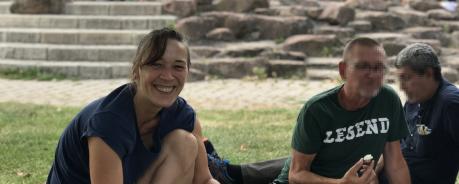Picknick: Jennifer Adler lächelt in die Kamera. Vor ihr ist eine Picknickdecke mit Essen. Neben ihr sind Menschen, deren Gesichter gepixelt sind.