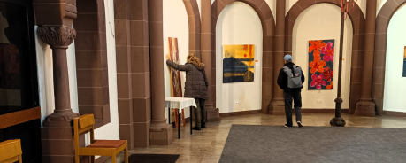 zwei Menschen schauen sich Bilder an. Sie sind nur von hinten zu sehen.