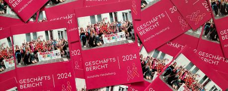 Foto: Viele Geschäftsberichte der Aidshilfe liegen auf und untereinander.