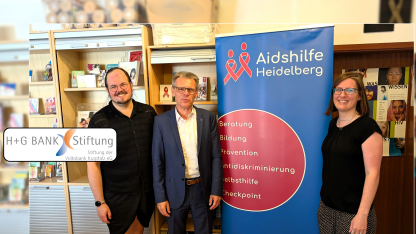 Peter Abelmann, Michael Hoffmann und Juliane Schurig stehen neben einem Roll-up der Aidshilfe
