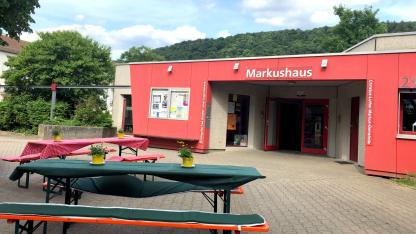 Hier ist die Front des Markushauses in der Südstadt zu sehen. Davor stehen schön gedeckte Bierbänke und -Tische.