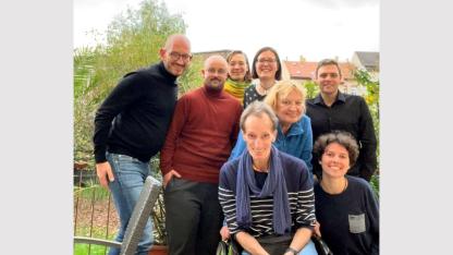 Gruppenbild auf der Terasse der AIDS-Hilfe: 7 Personen stehen zusammen und lächeln in die Kamera.