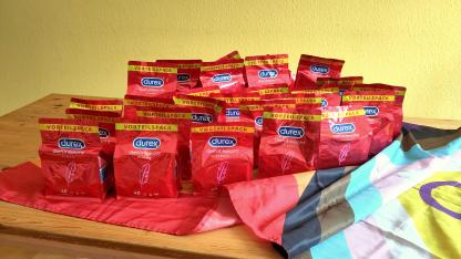 Auf einer Progress-Flag stehen viele Packungen voller Durex-Kondome. Die Packungen sind rot. Das Durex-Logo blau.