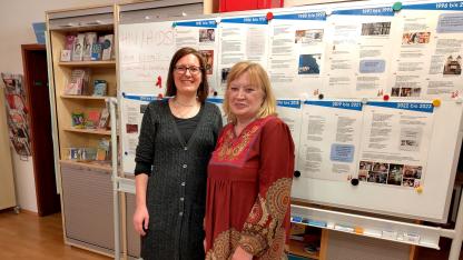 Juliane und Elke stehen vor einem Board mit einem Zeitstrahl zur Geschichte der HIV Epidemie und der Aidshilfe Heidelberg
