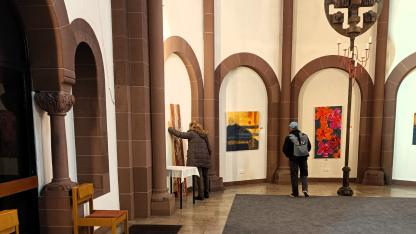 zwei Menschen schauen sich Bilder an. Sie sind nur von hinten zu sehen.