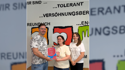 Patrick steht mit jungen Menschen vor einer bunten Wand.