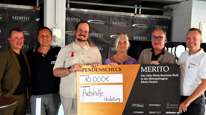 Gruppenfoto: Peter und Sigrid halten mit mehreren anderen Menschen einen großen Scheck für die Aidshilfe