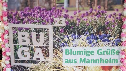 Poster der Bundesgartenschau in Mannheim. Sehr bunt mit vielen Pflanzen und Blüten. Davor der Schriftzug BUGA und Blumengrüße aus Mannheim. Unten das Logo der Deutschen Bahn